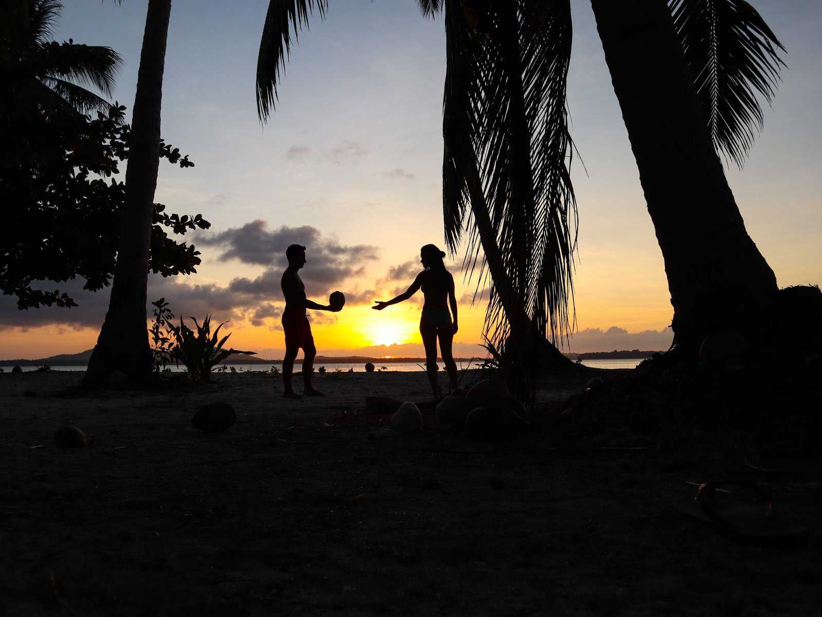 Lovely couple watching sunset with palm trees in Candaraman Island in Balabac Philippines
